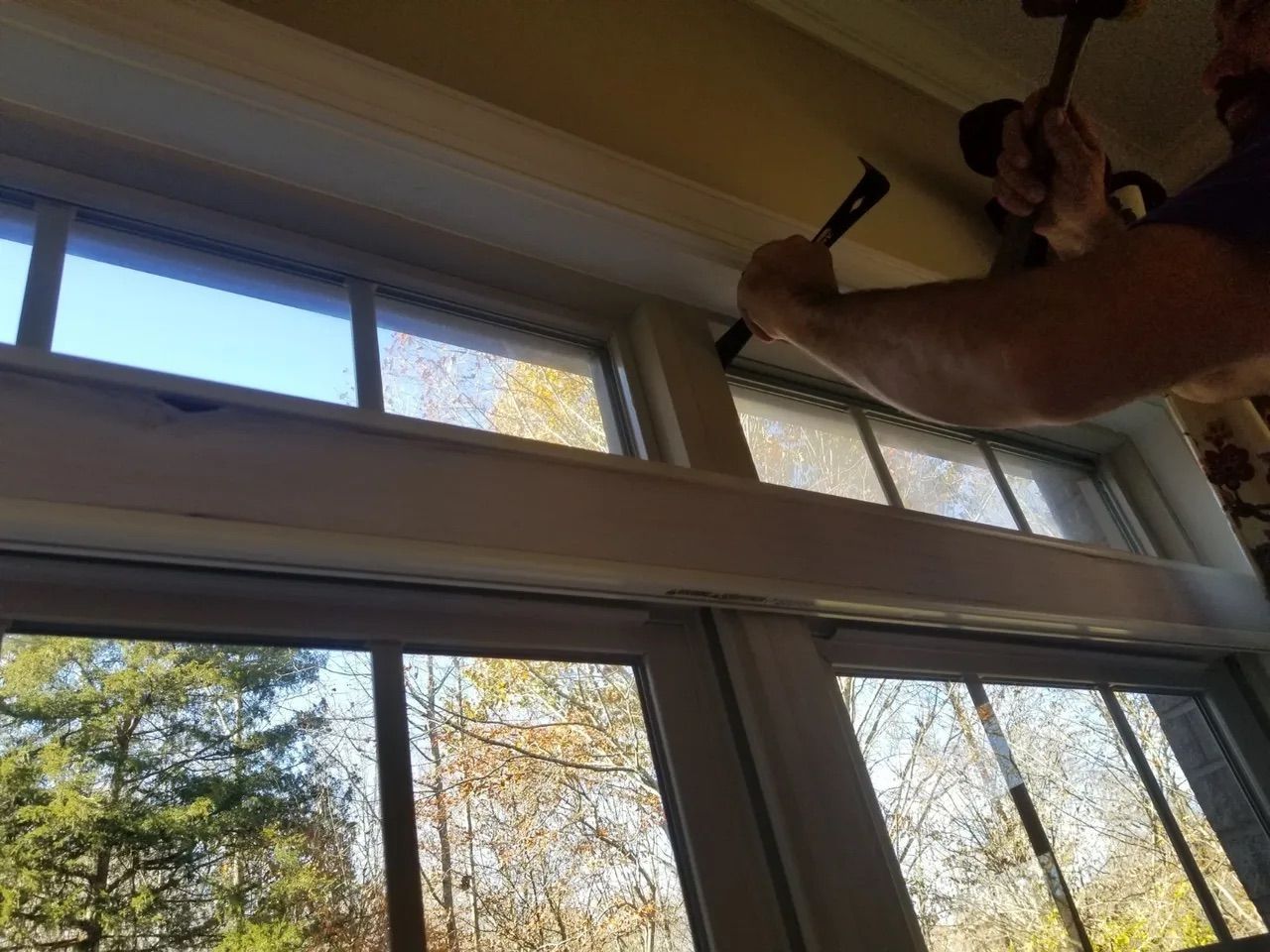 A man is hammering a window frame with a hammer.