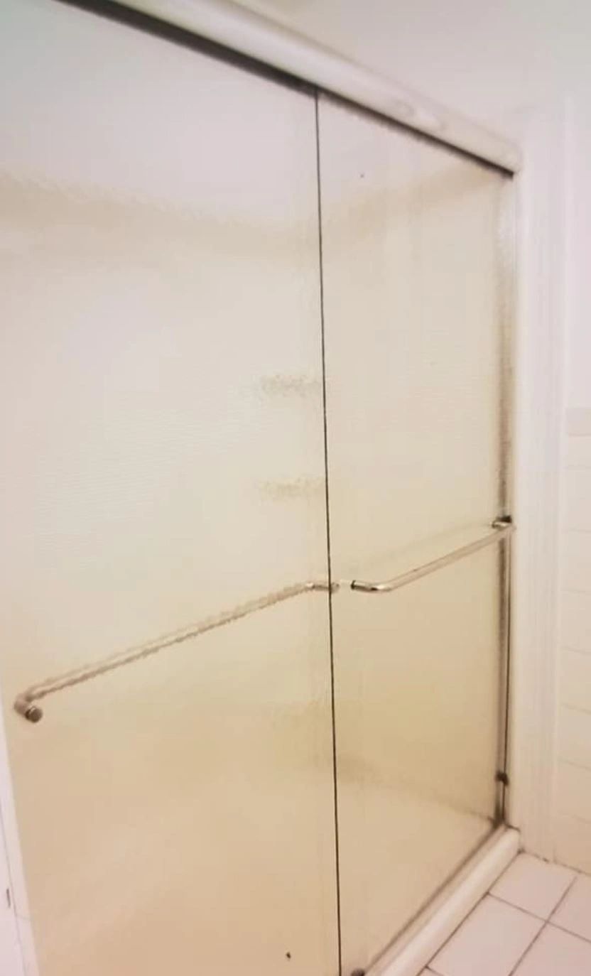 A bathroom with a sliding glass shower door and a towel rack.