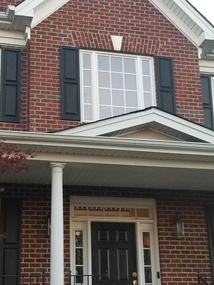 A brick house with black shutters on the windows