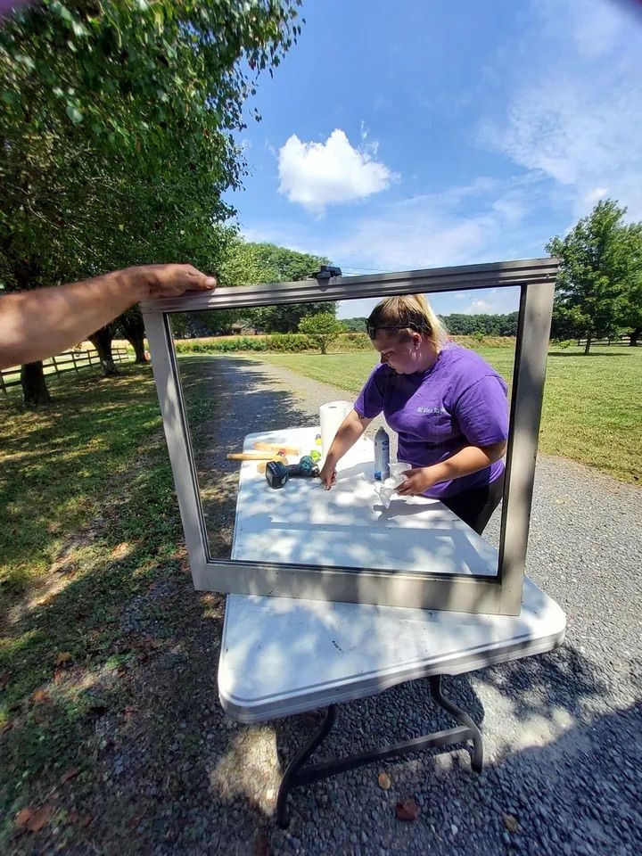 A woman is sitting at a table holding a picture frame.