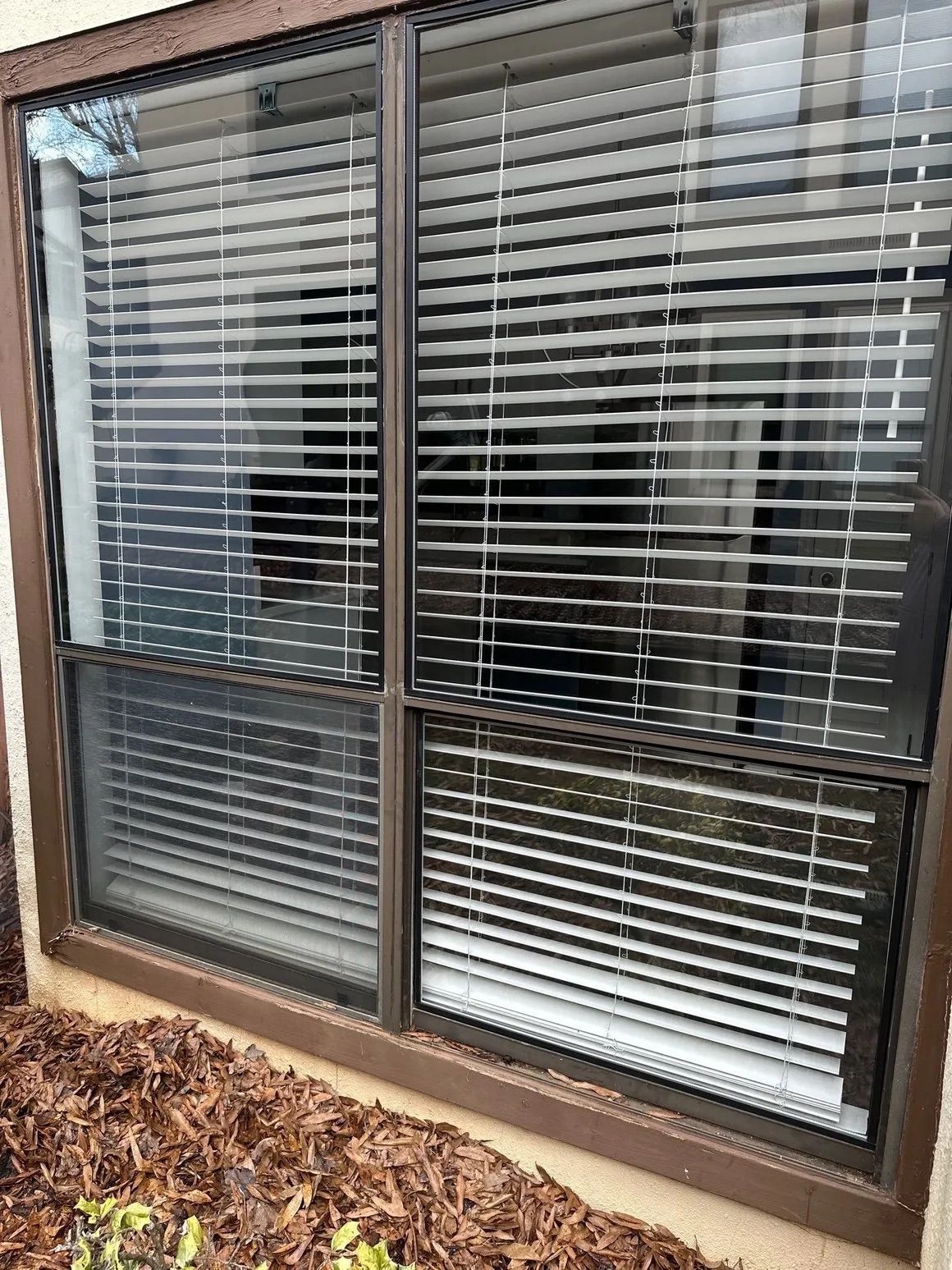 A window with blinds on it is sitting on the side of a building.