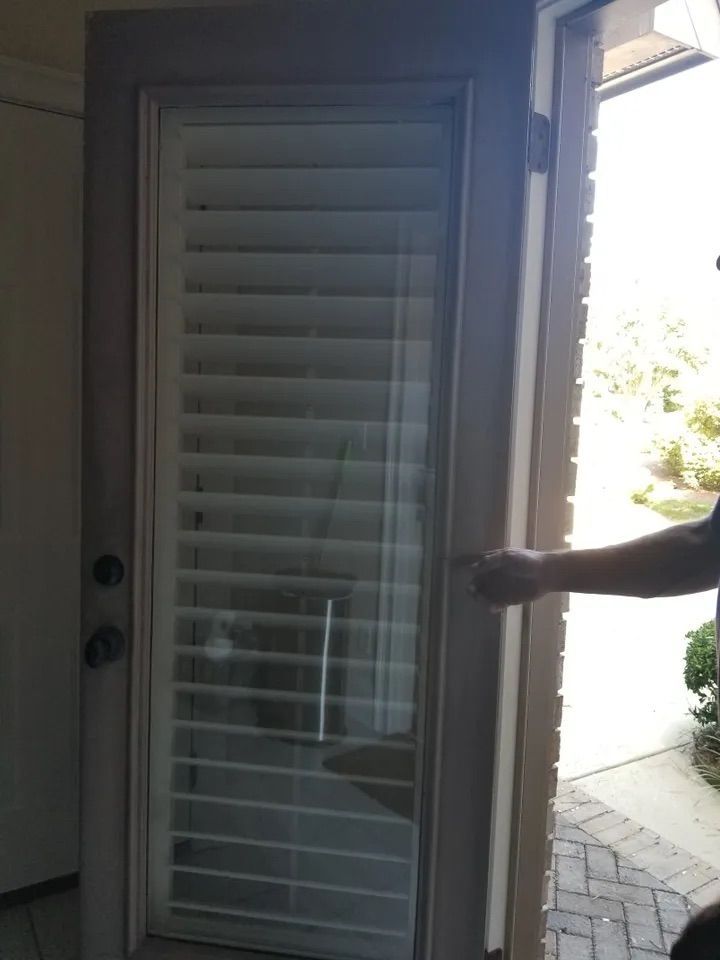 A person is opening a door with shutters on it