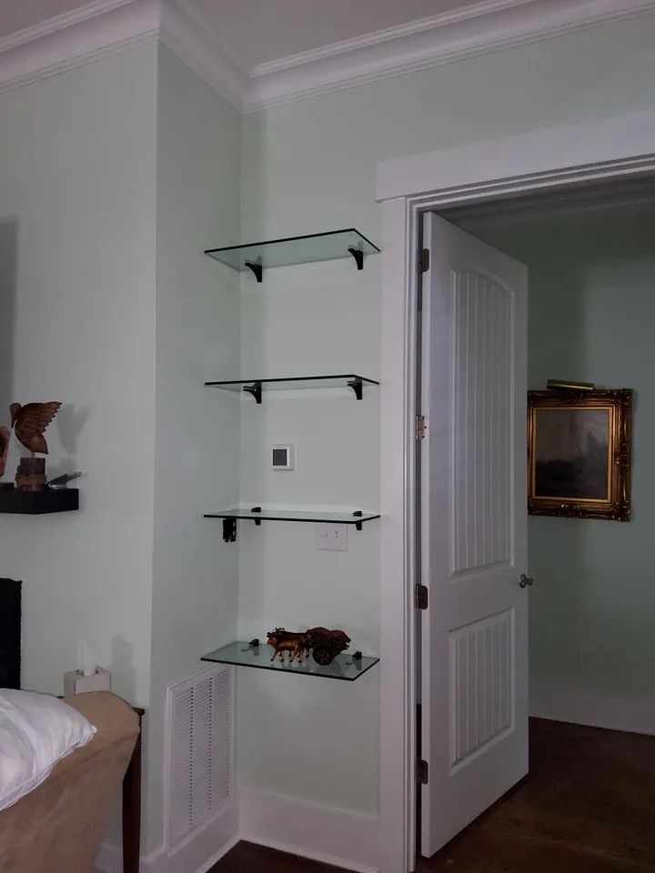 A bedroom with glass shelves and a picture on the wall