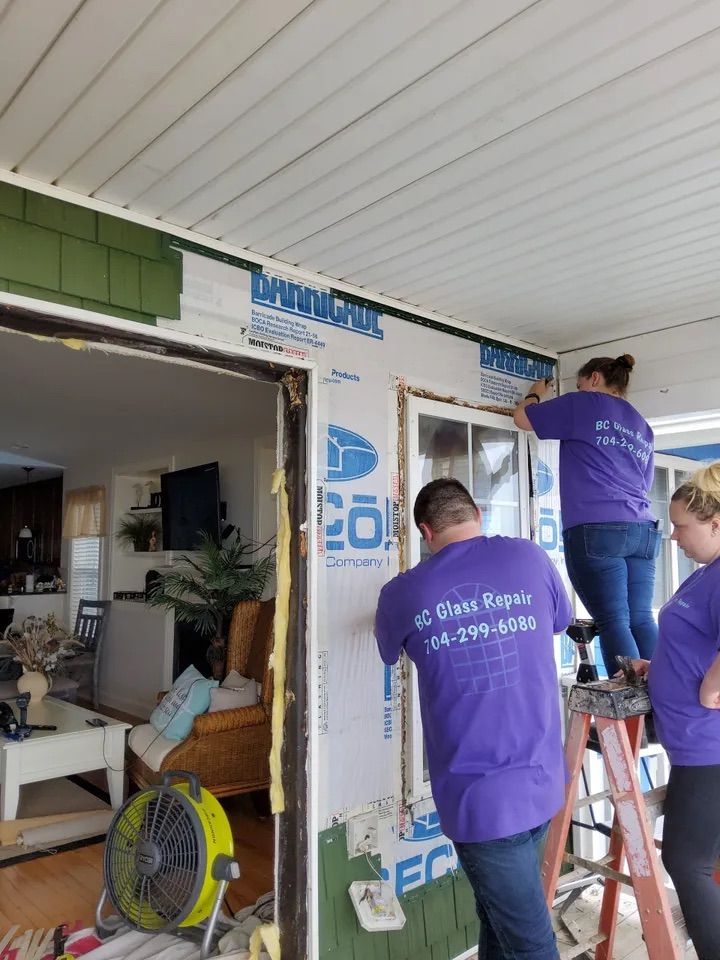 A group of people in purple shirts are working on a house.