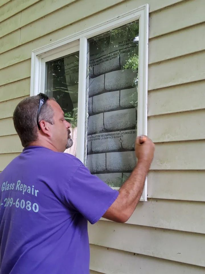 A man in a purple shirt is fixing a window