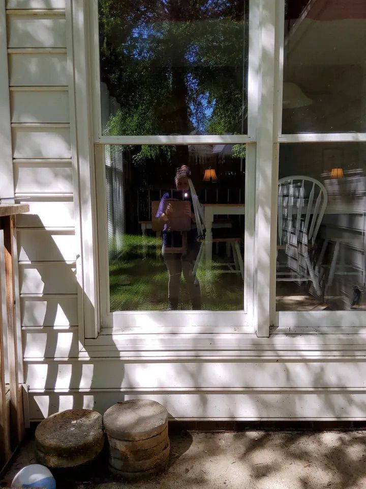 A reflection of a person in a window of a house