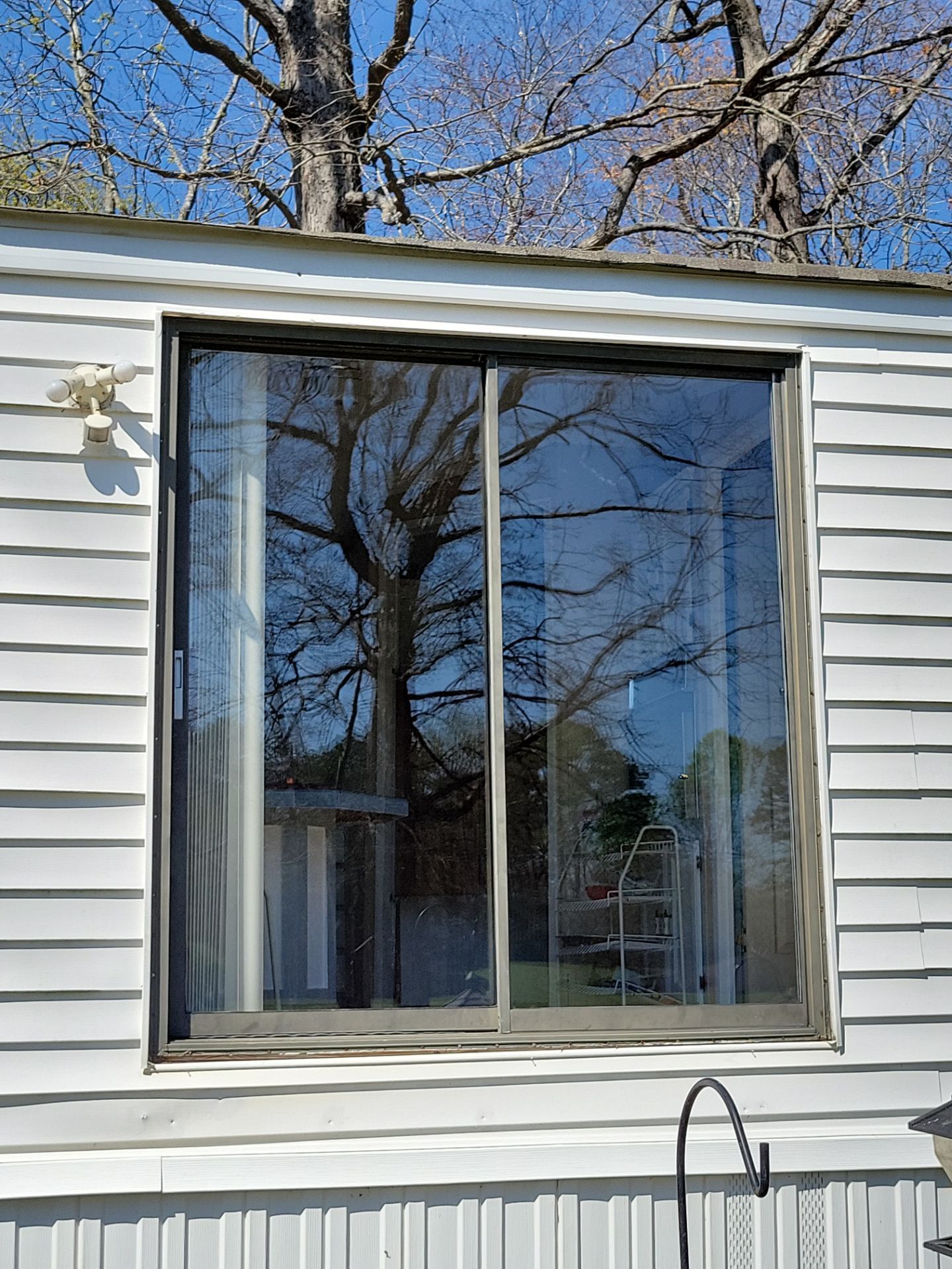 A white mobile home with a large sliding glass window.