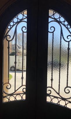 A close up of a wrought iron door with a glass window.