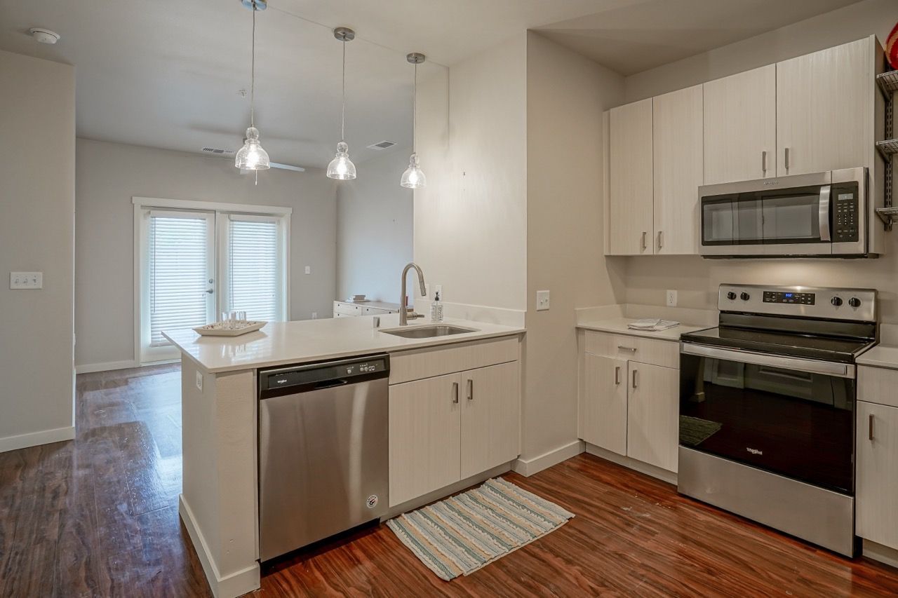 Modern kitchen with an island, stainless steel appliances, and white cabinets at Capitol Flats, offering apartments in Santa Fe, NM.