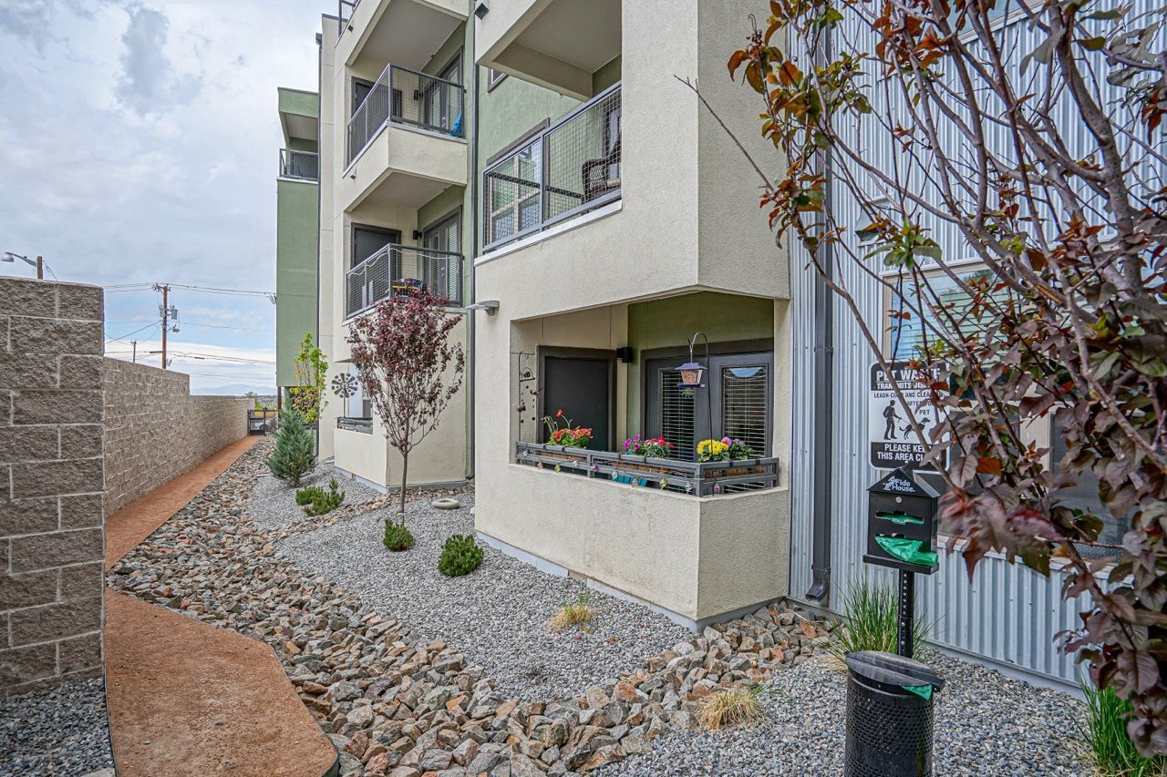 Exterior view of a multi-story apartment building with balconies and a small front patio at Capitol Flats, offering Santa Fe apartments.