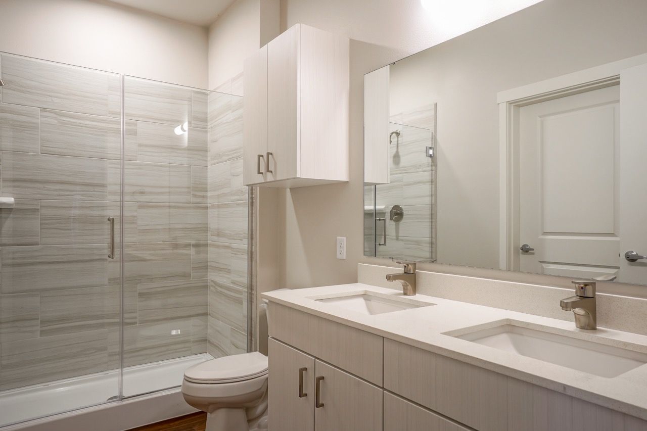 Modern bathroom with glass-enclosed shower, double sink vanity, and white cabinetry at Capitol Flats, offering apartments for rent in Santa Fe, NM.