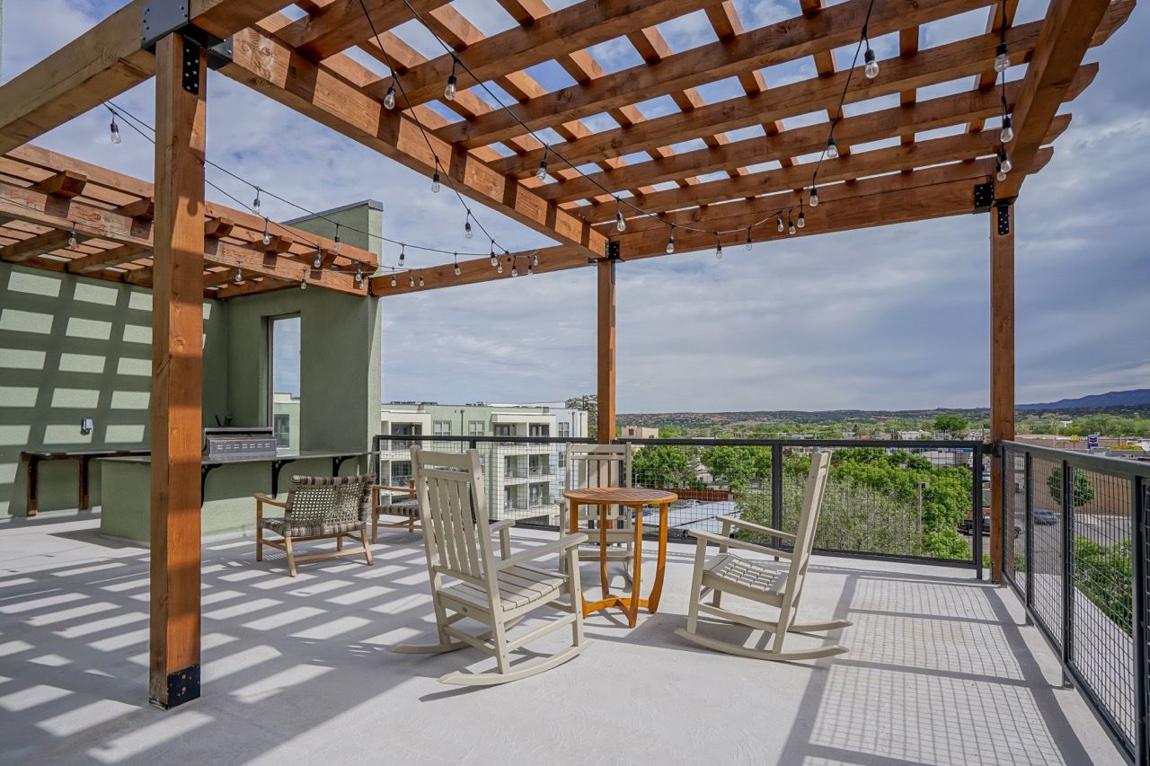 Rooftop terrace with a wooden pergola, string lights, grill, and outdoor seating at Capitol Flats, offering pet-friendly apartments for rent in Santa Fe, NM.