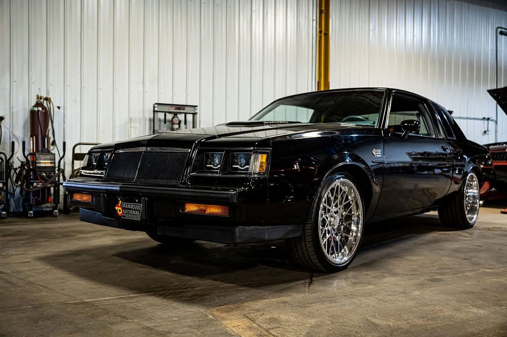 Black Buick Regal in a garage, chrome wheels, orange turn signals.