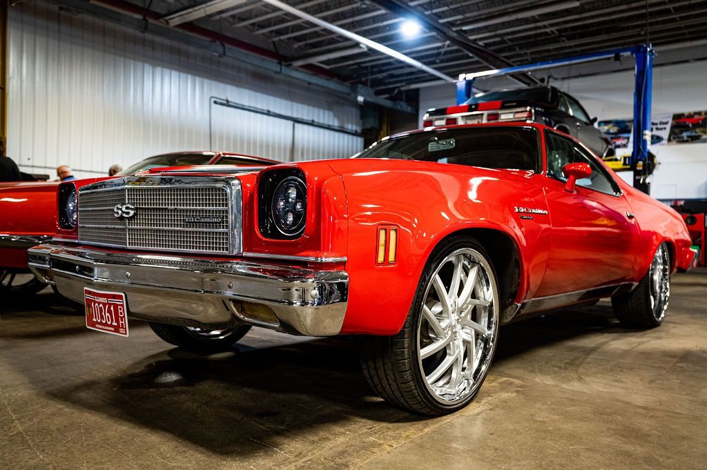 Red classic car with chrome accents and large rims in a garage.