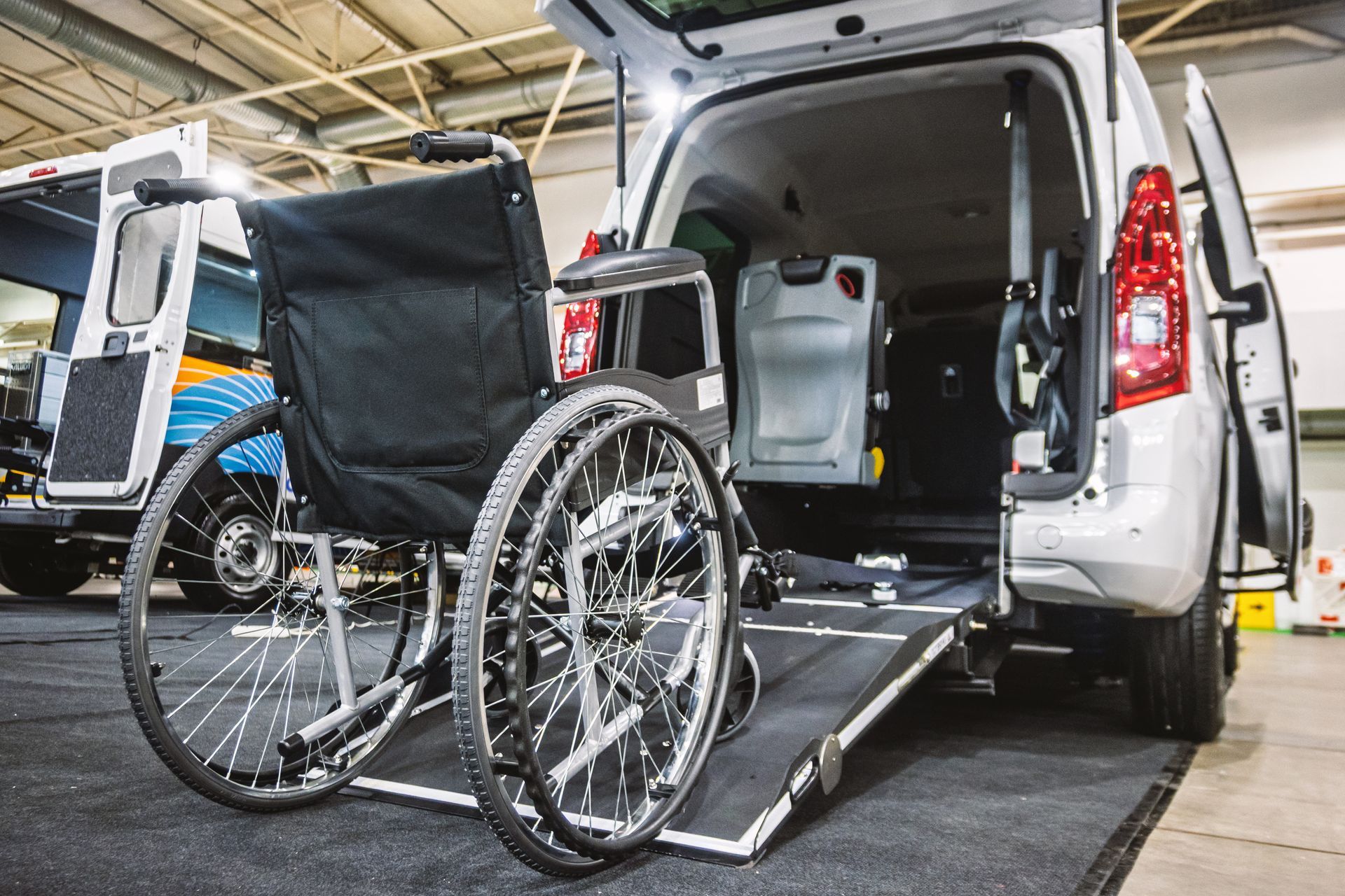 Wheelchair on a vehicle lift at the back of a van, ready for loading.