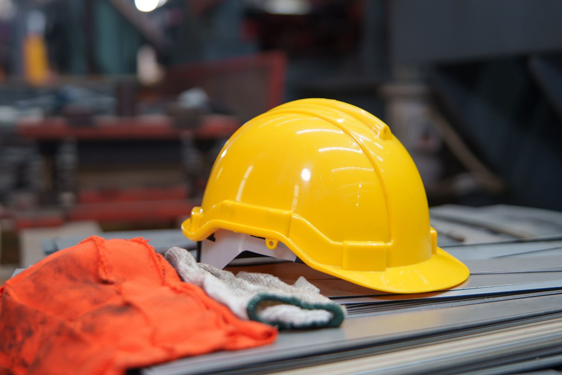 Yellow hard hat and orange work gloves on a workbench in a workshop Yellow hard hat and orange work gloves on a workbench in a workshop