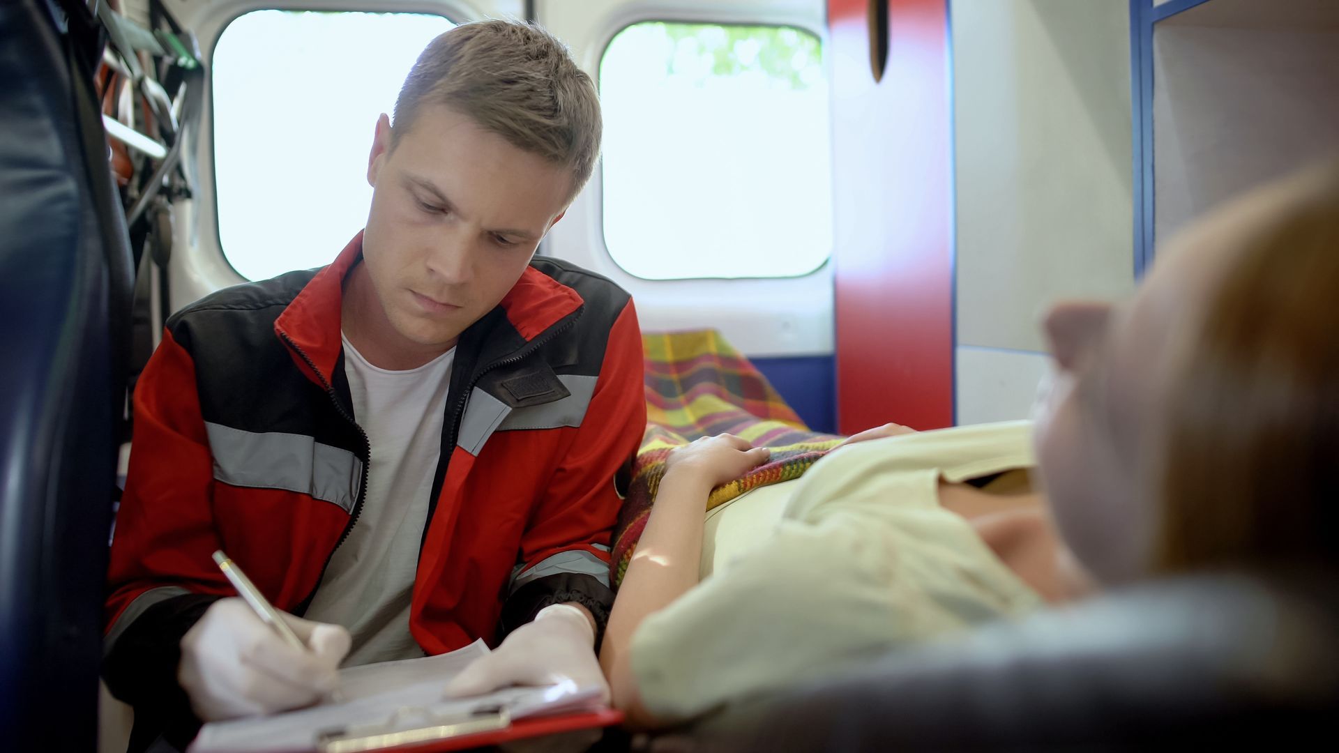 A doctor is filling a medical form in an ambulance. A doctor is filling a medical form in an ambulance.