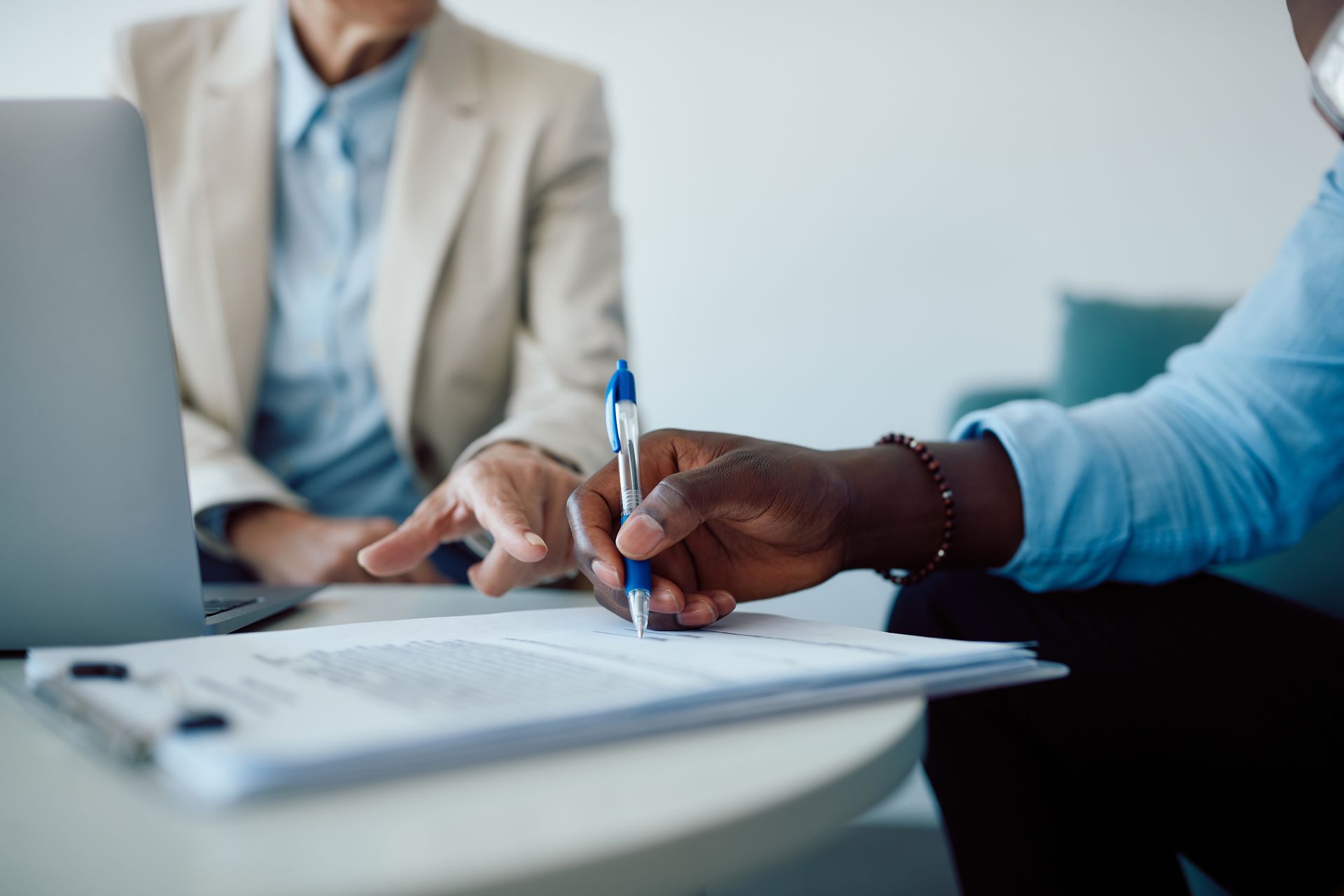 Client signing business contract document with pen during professional consultation meeting.