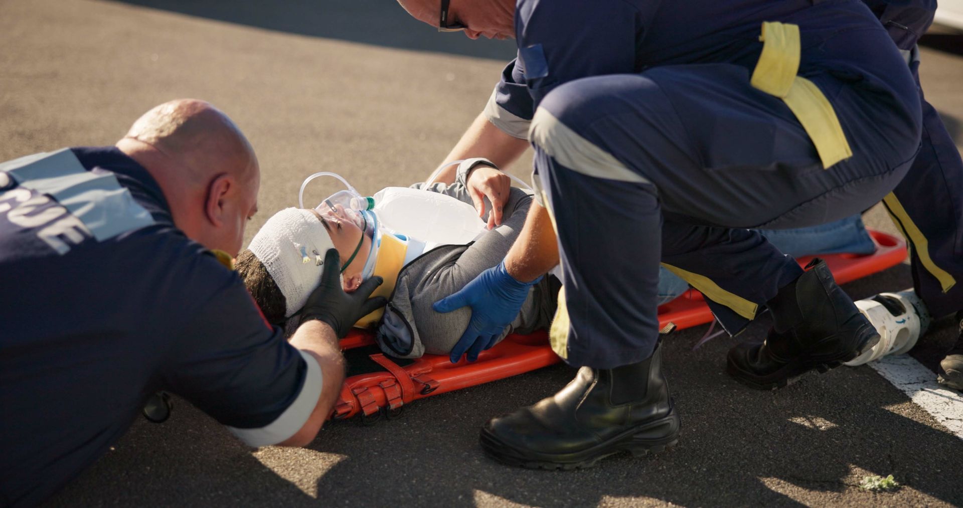 Emergency responders treating an injured person on a stretcher after an accident.
