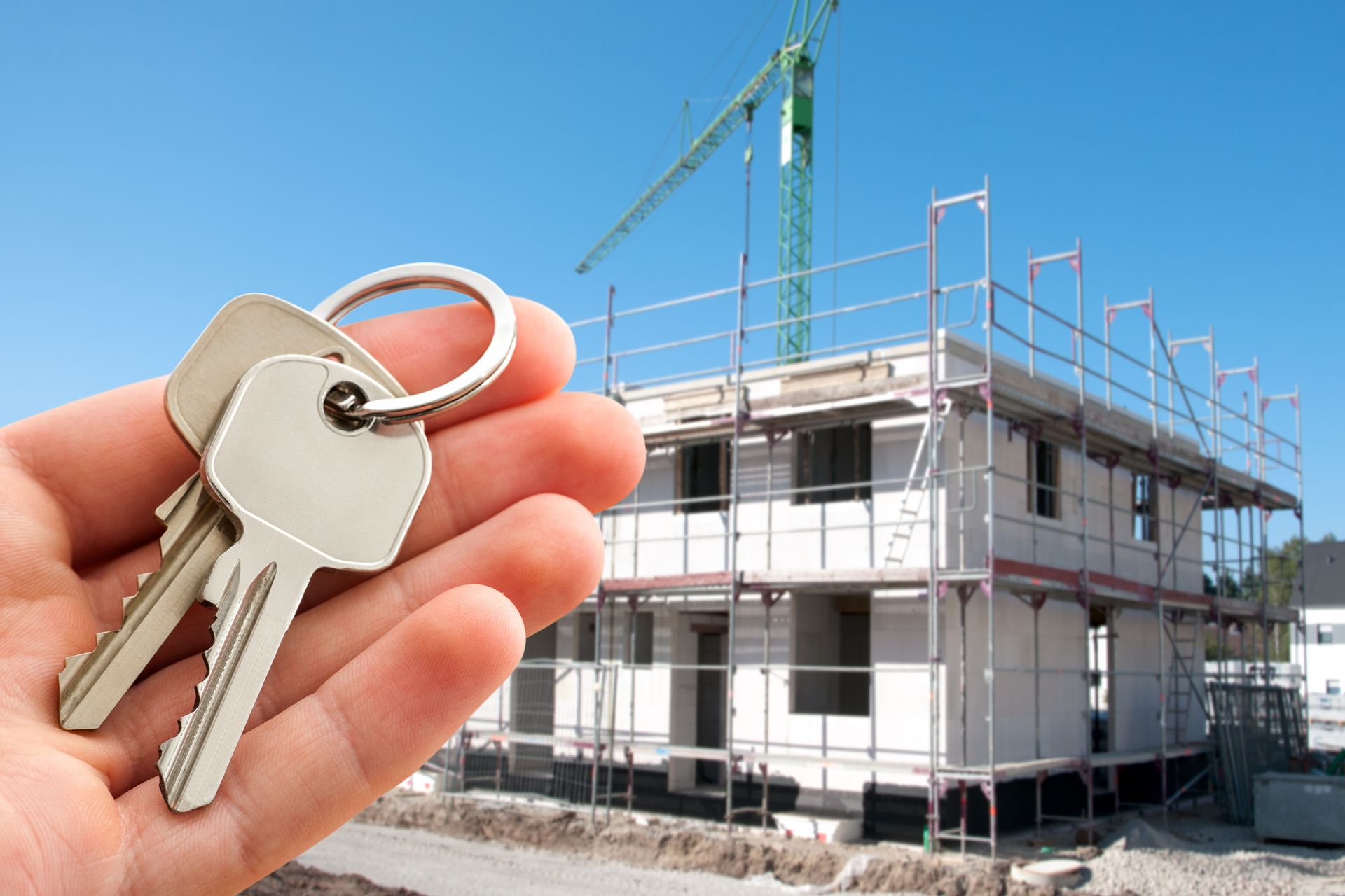Hand holds keys with a building on background, showcasing contractors insurance.