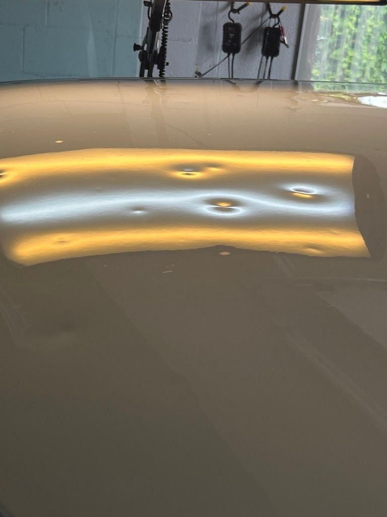 A car's metallic surface reflecting dents under a specialized light, revealing damage before repair. A car's metallic surface reflecting dents under a specialized light, revealing damage before repair.