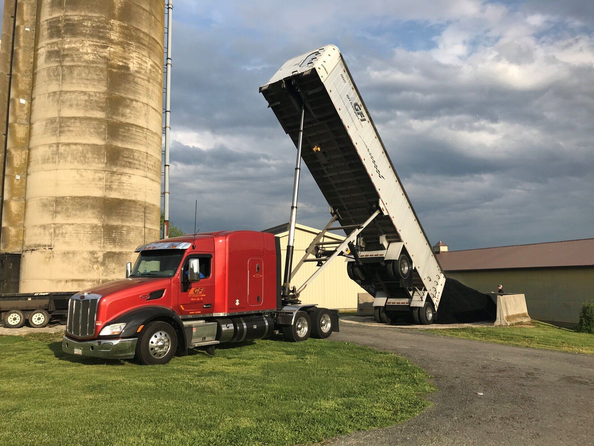 Red semi truck dump trailer unloading coal