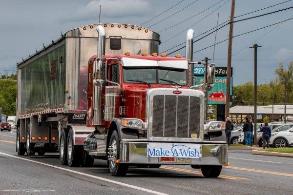 A red GFI Transport dump trailer semi truck is parked in front of a building.