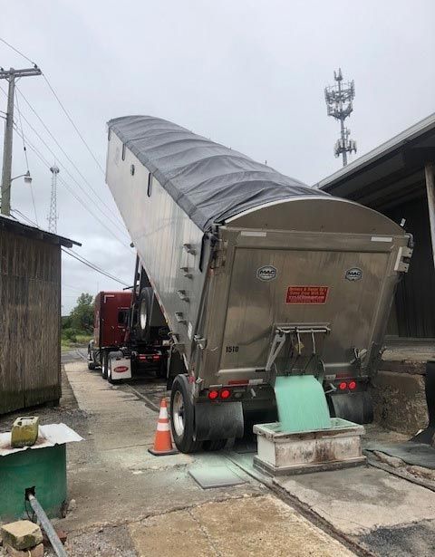 A large dump truck is sitting on a scale in front of a building.