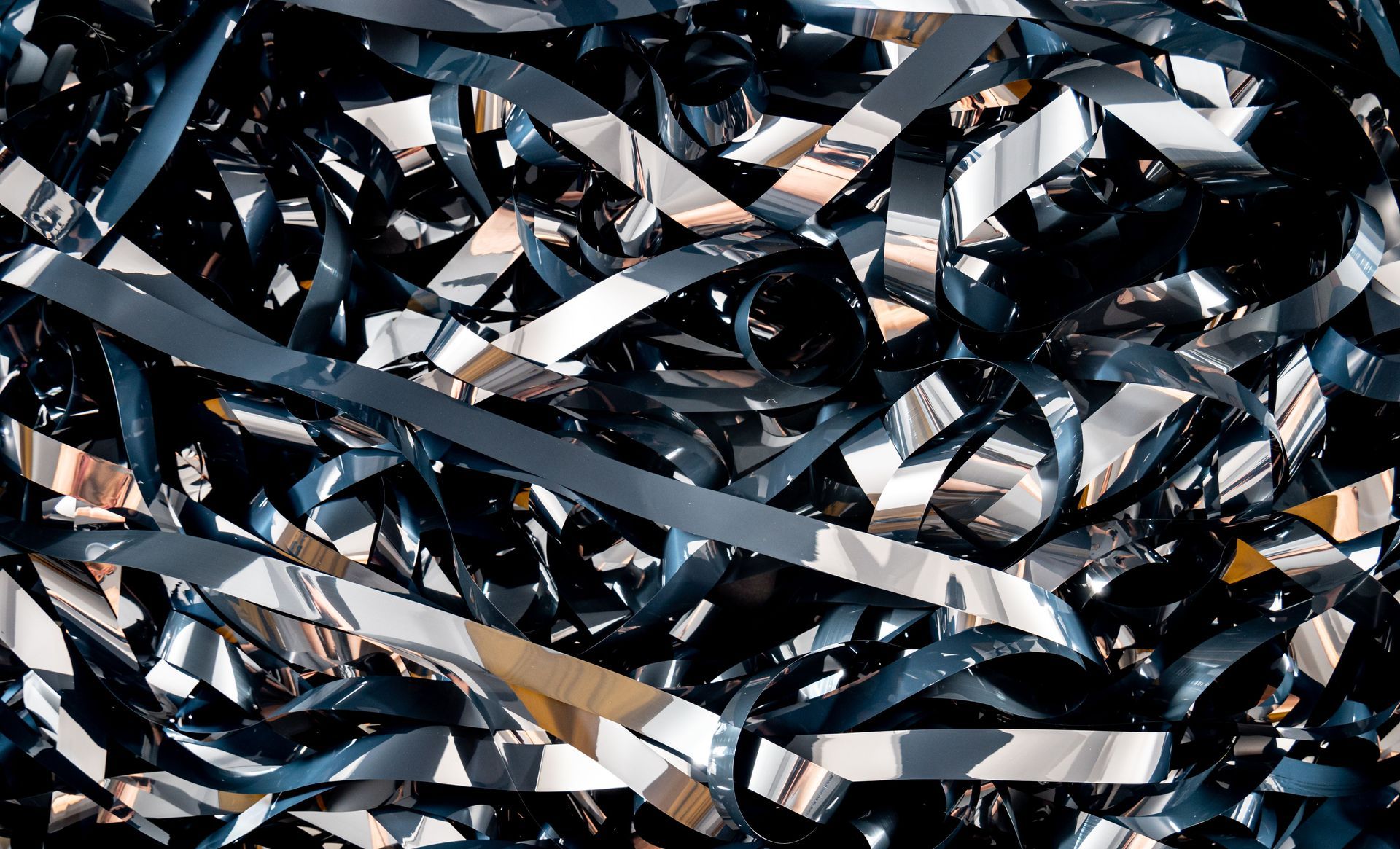 Close-up of tangled black and silver reflective strips creating an abstract metallic texture.
