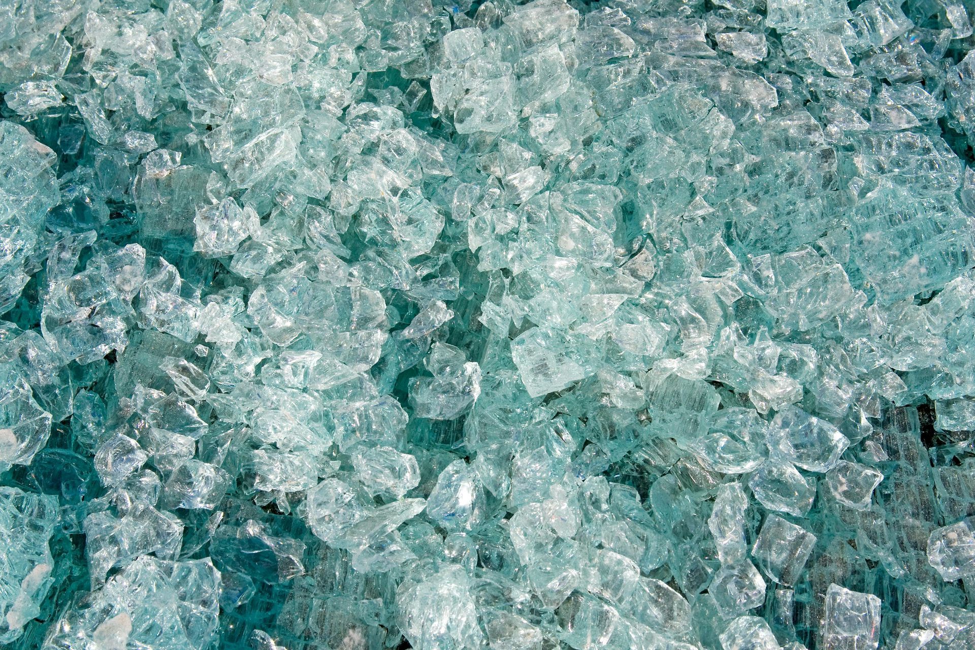 Close-up of scattered, broken pieces of aqua-tinted glass.