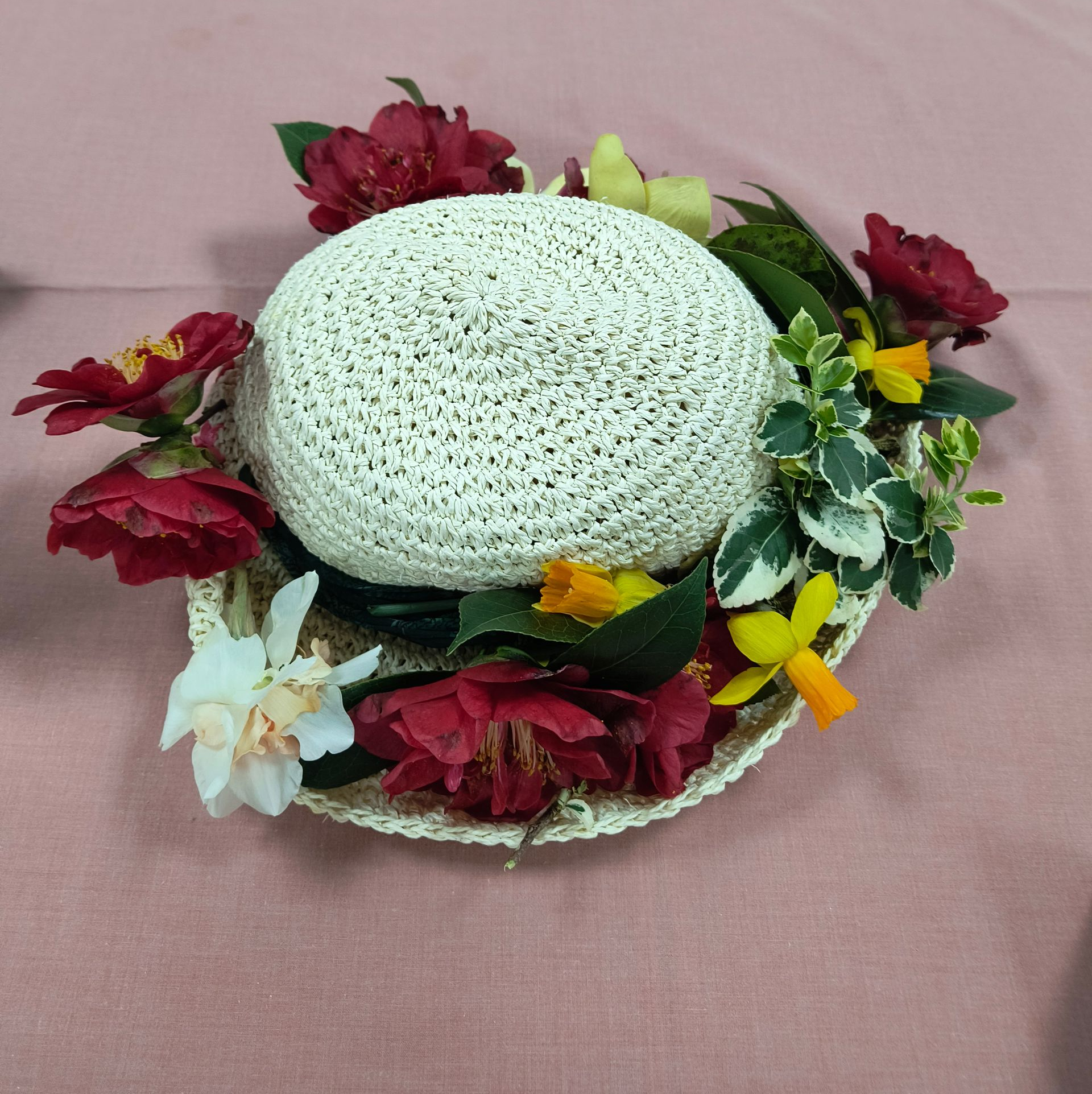 Photo shows a straw hat deocrated with a variety of flowers