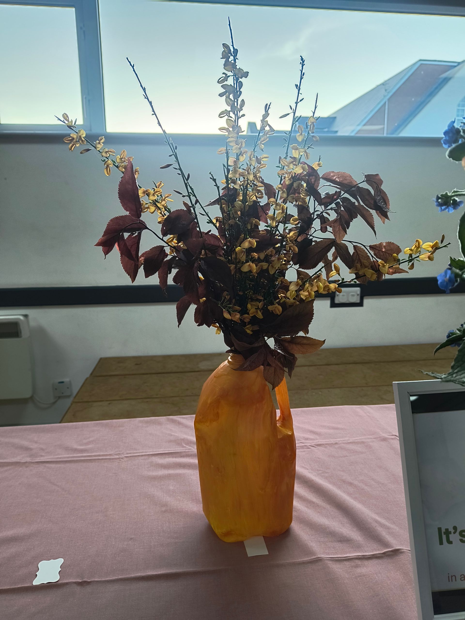 Photo shows a cleaned food can containing an arrangement of blue, purple, cream and yellow flowers