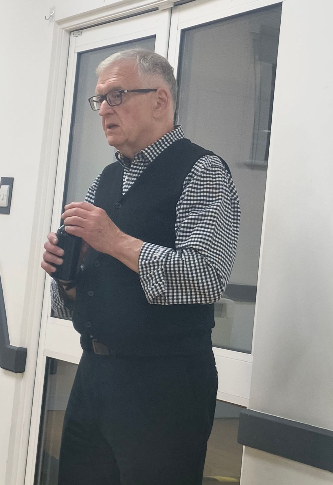 Photo of speaker Alan Gregory standing at the front of the hall responding to members' questions.  
