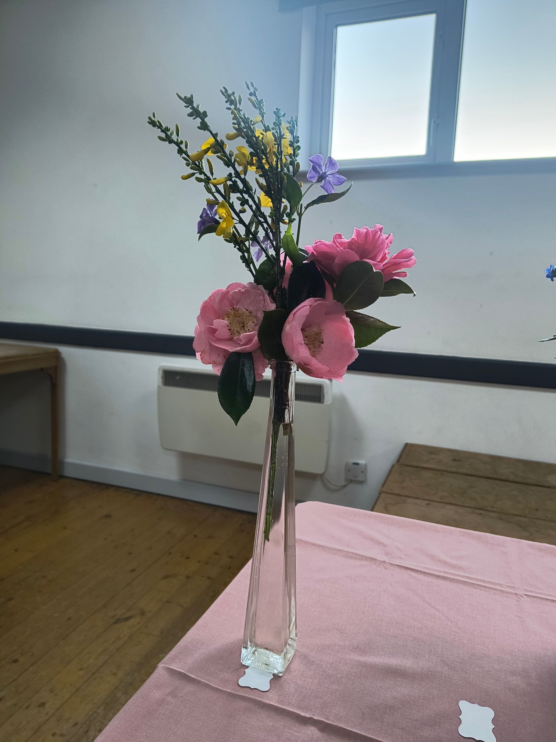 Photo shows an empty 2 litre plastic milk carton painted yellow with an arrangement of brown leaves and yellow flowers
