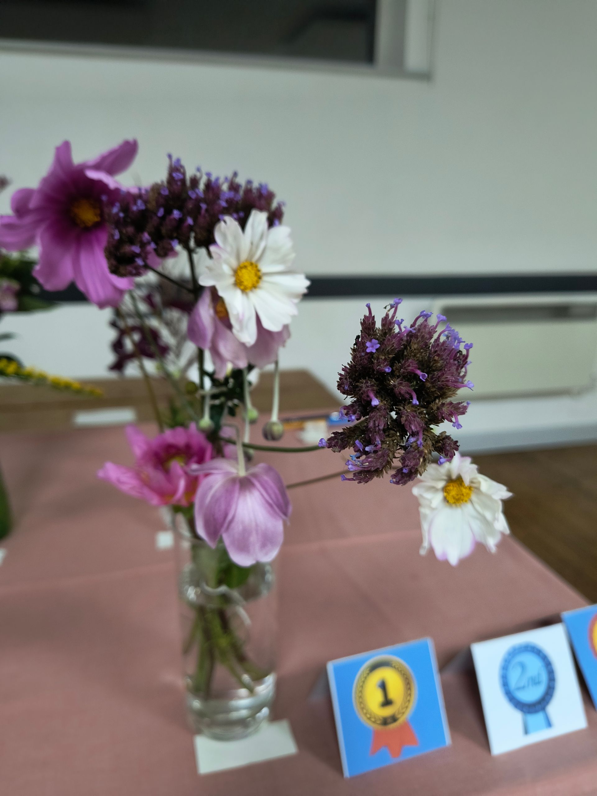 Photos shows purple, pink and white flowers in a glass vase