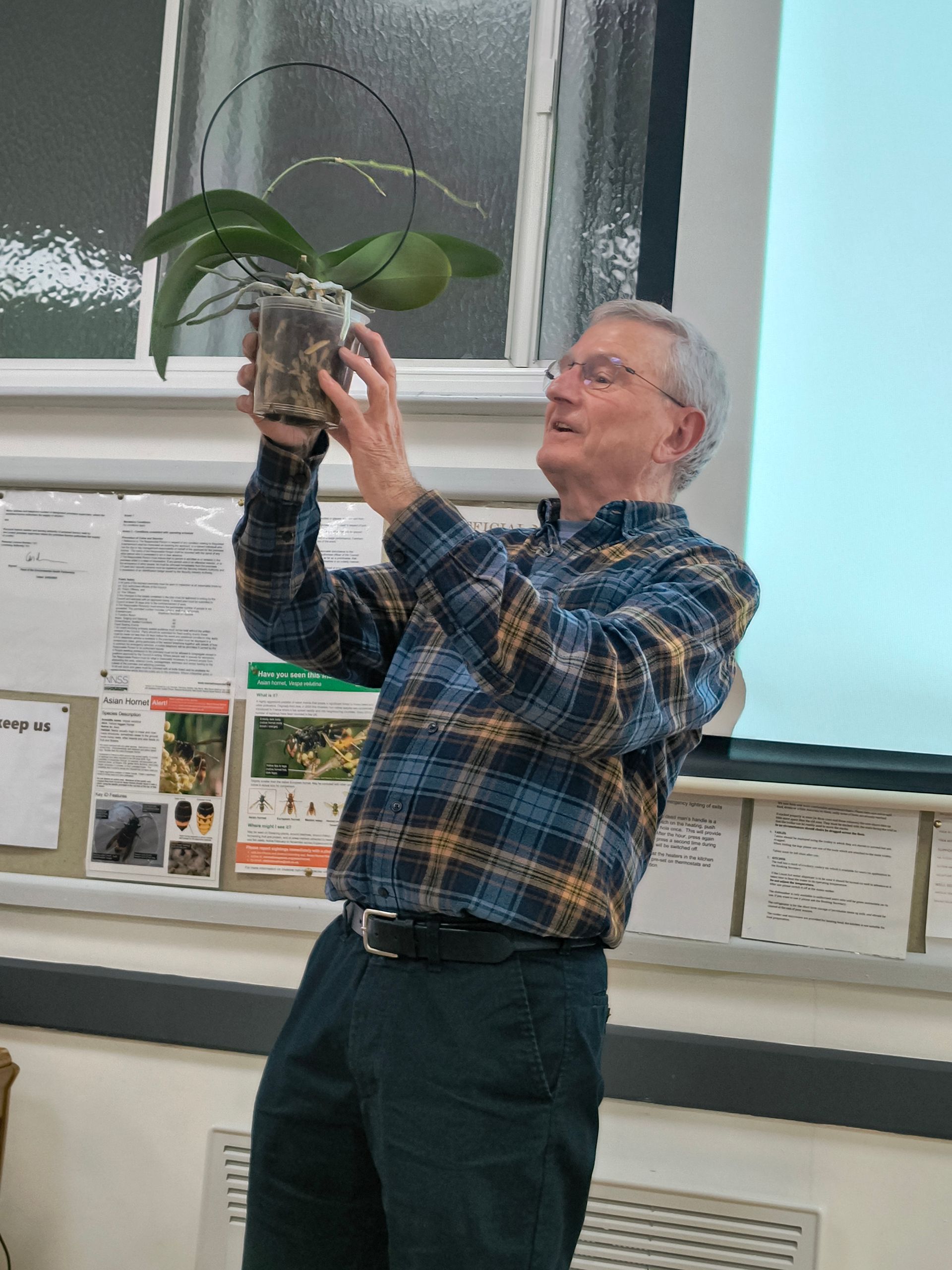 Peter admires a healthy orchid plant brought in by a member