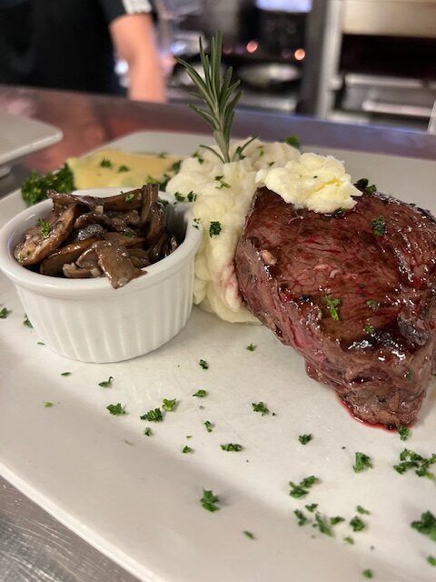 A white plate topped with a steak , mashed potatoes and mushrooms.