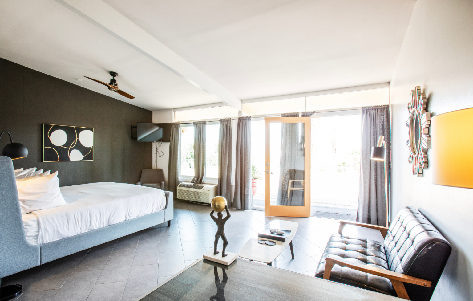 A hotel room with a bed , couch , coffee table and a statue.