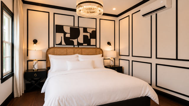 Elegant bedroom with white bed, black-and-cream paneled walls, and modern chandeliers