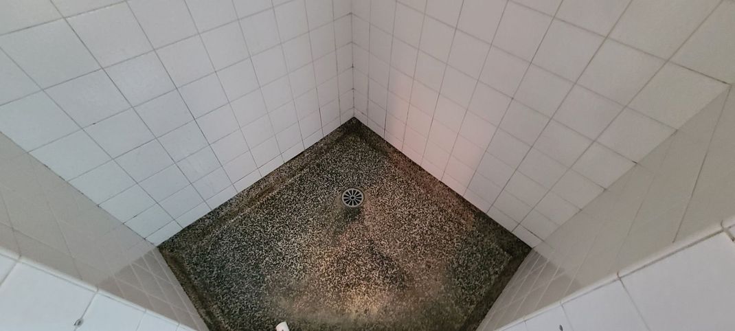 A bathroom with white tiles and a dirty floor.