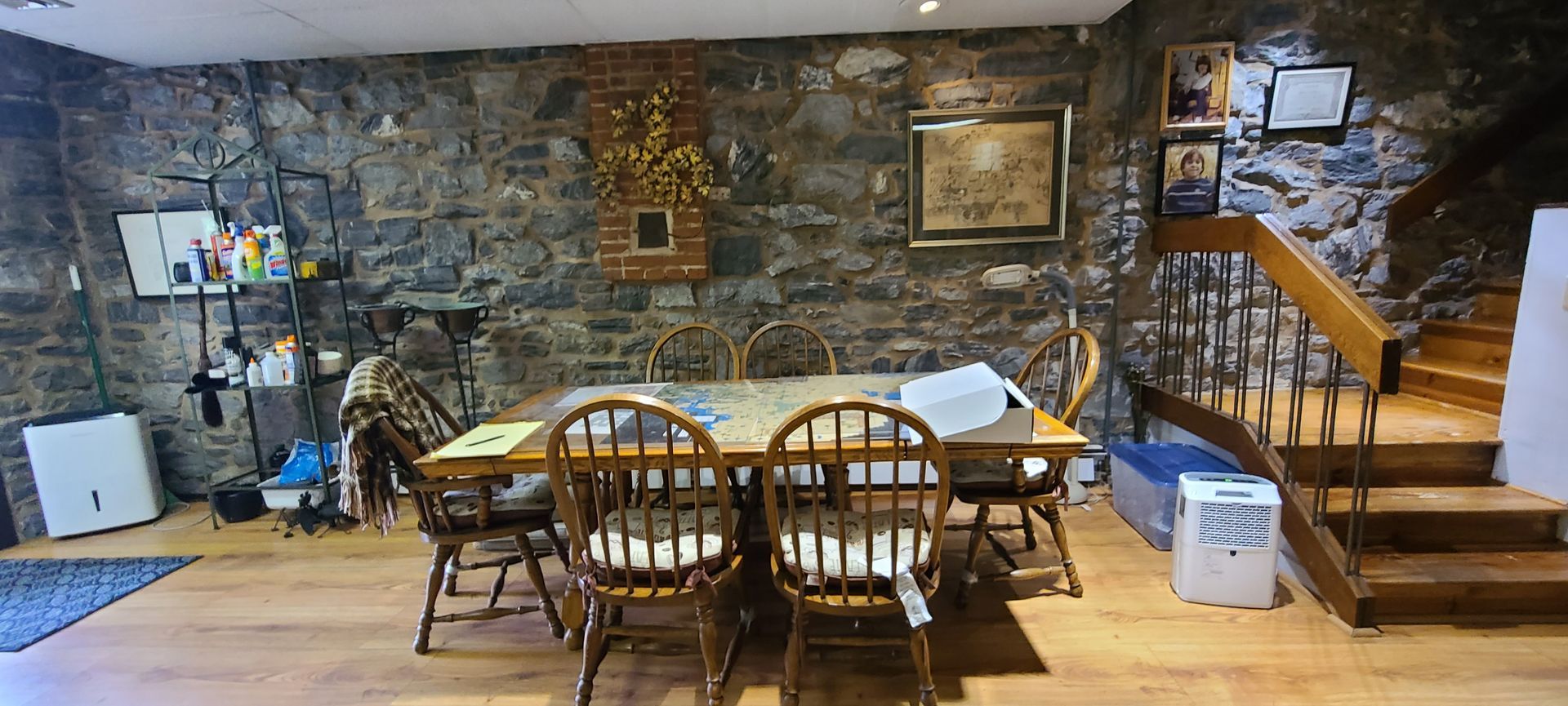 A dining room with a table and chairs in front of a stone wall.