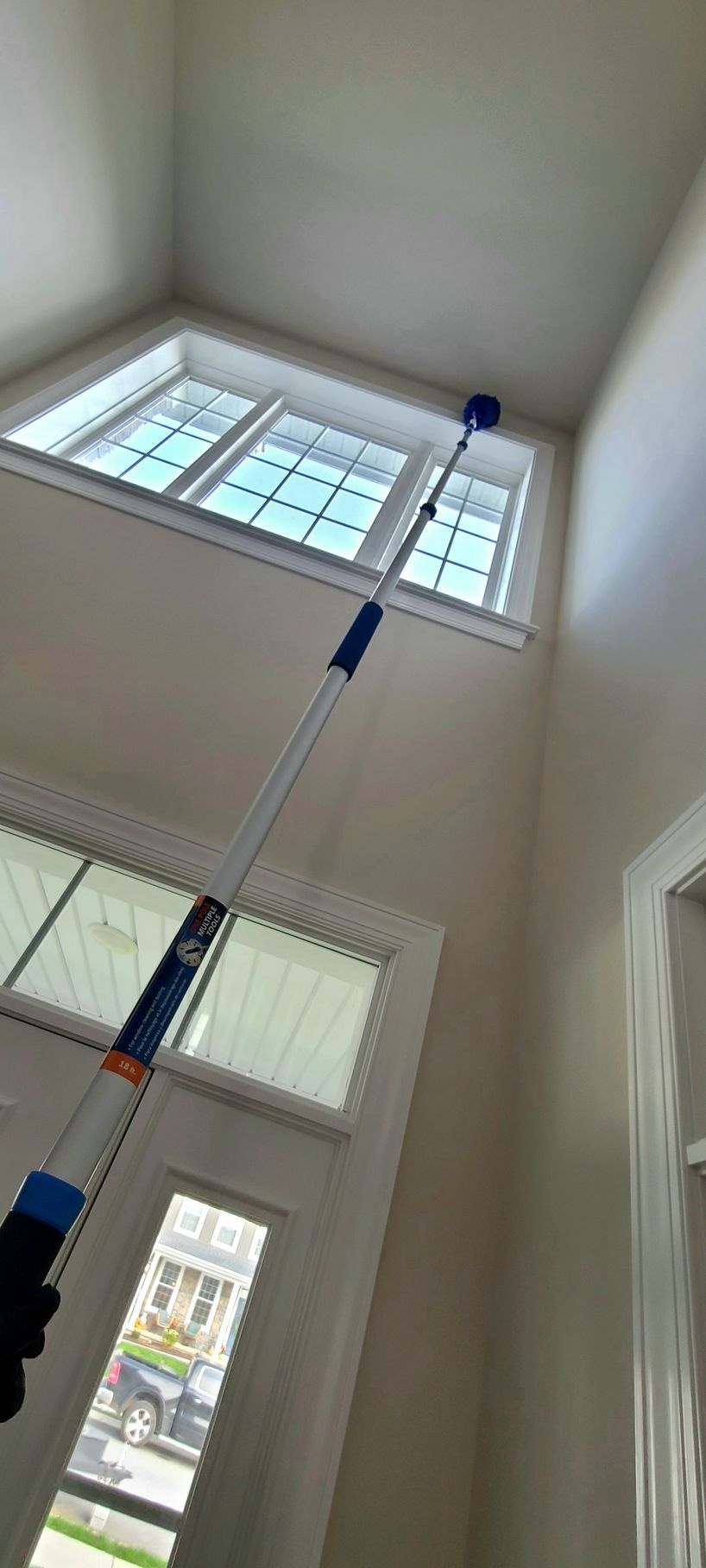 A person is cleaning the ceiling of a house with a mop.