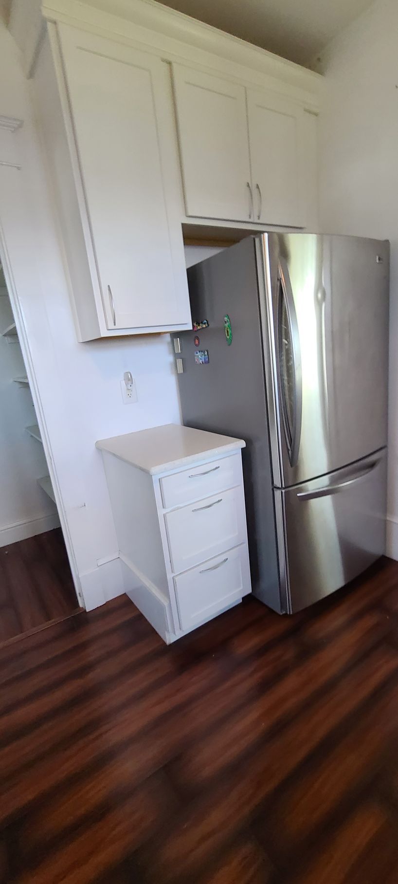 A stainless steel refrigerator is sitting in a kitchen next to a white cabinet.