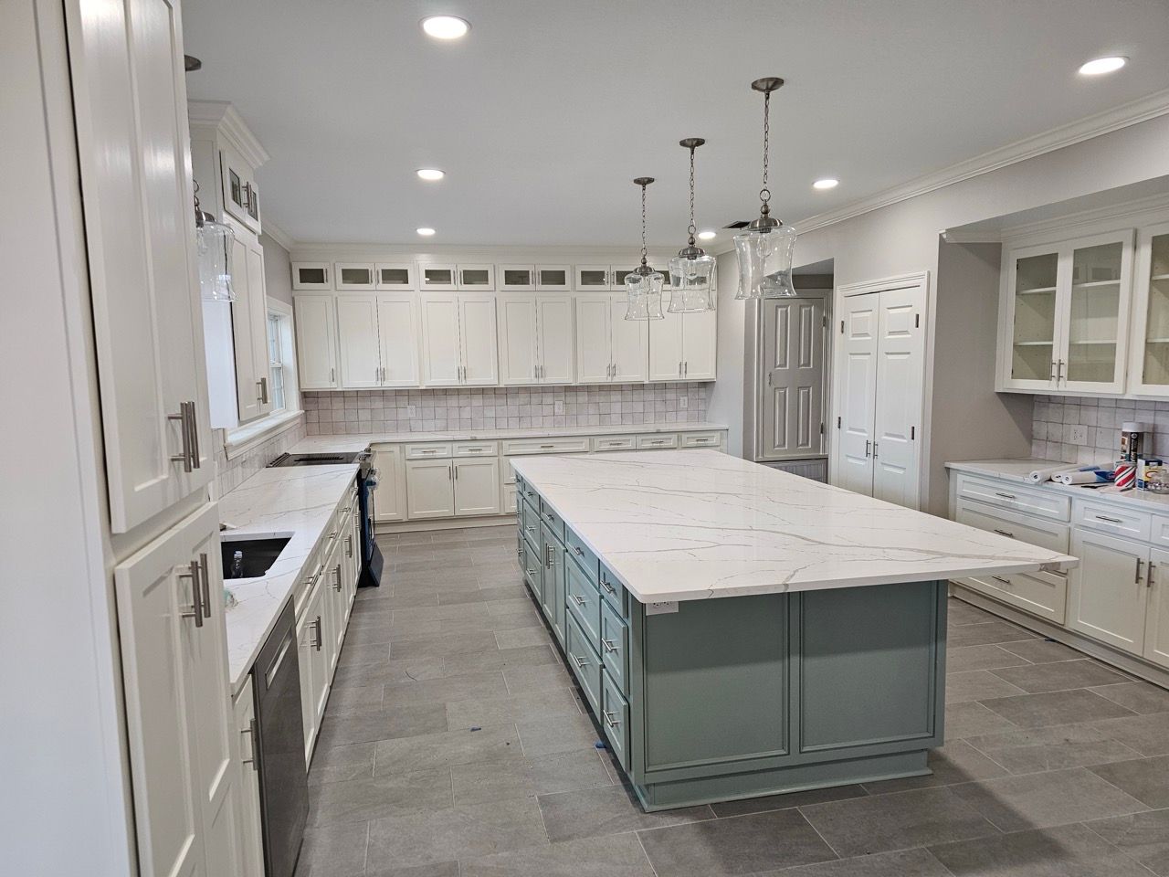 Bright modern kitchen with white cabinets, gray tile floor, and a large marble island.