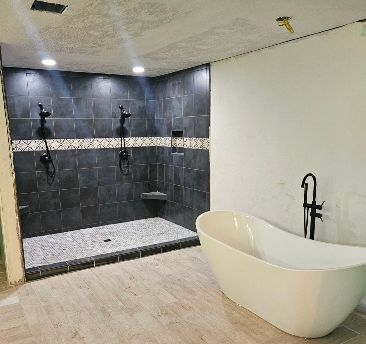 Modern bathroom with dark tile shower and a freestanding white soaking tub