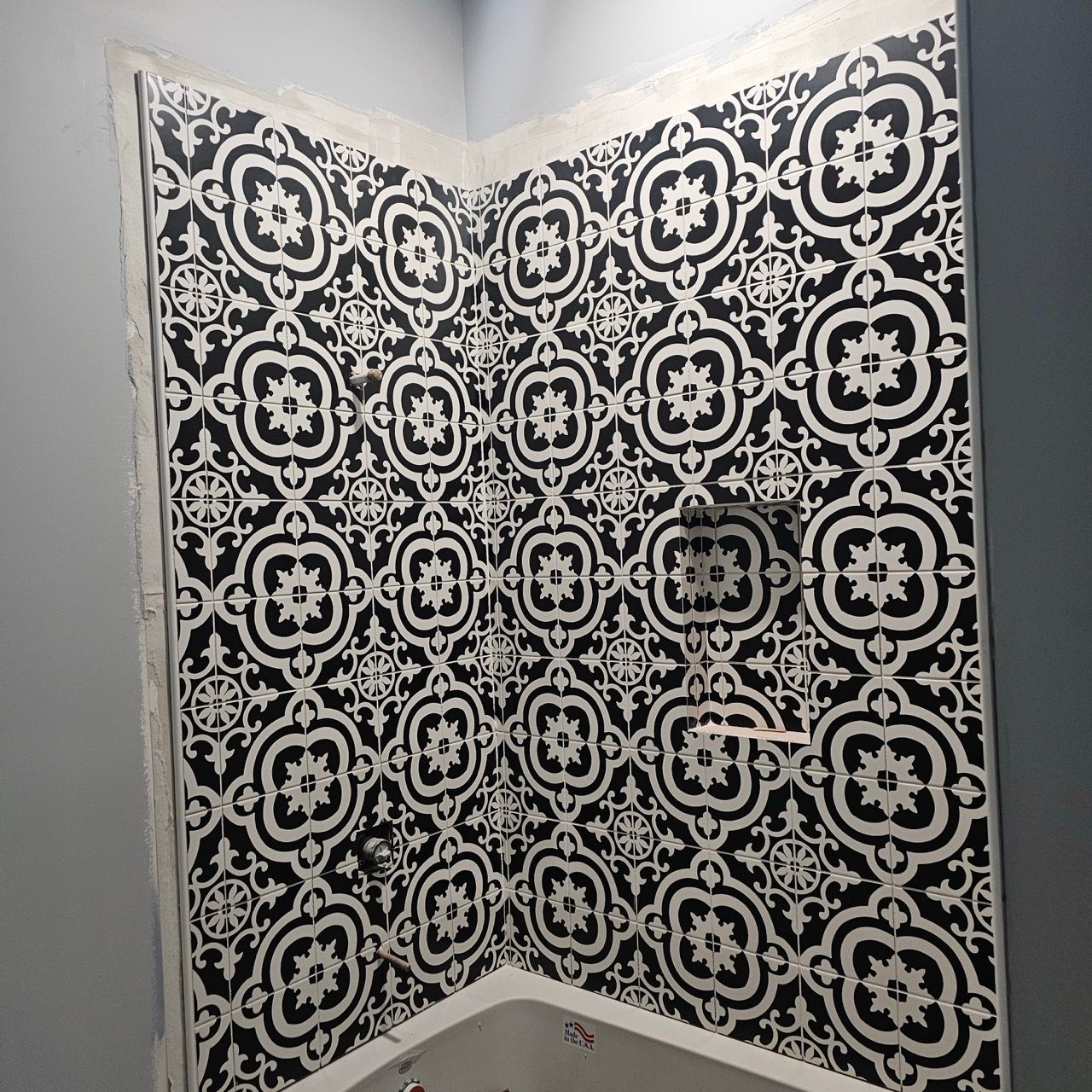 Black and white patterned tile on shower walls in a corner bathroom