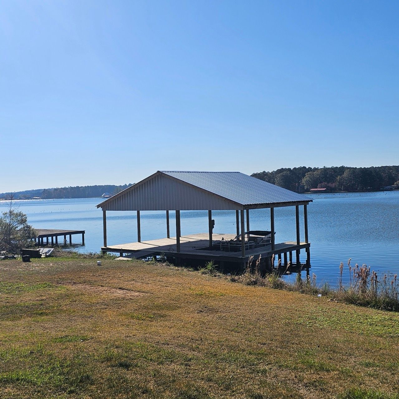 Lakeside dock with a striped-roof shelter under a clear blue sky