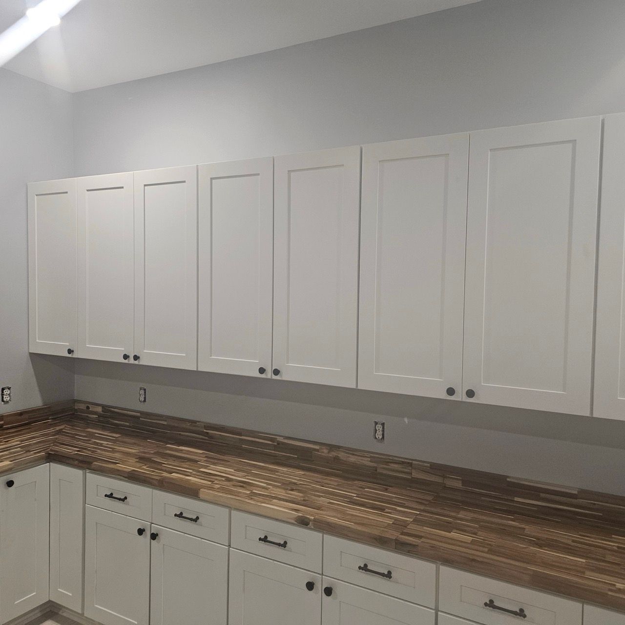 White kitchen cabinets with gold tile backsplash and light gray walls