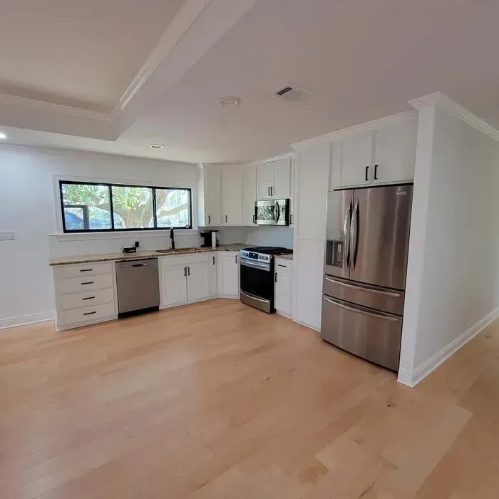 Modern, bright kitchen with white cabinets, stainless steel appliances, and light wood floors.