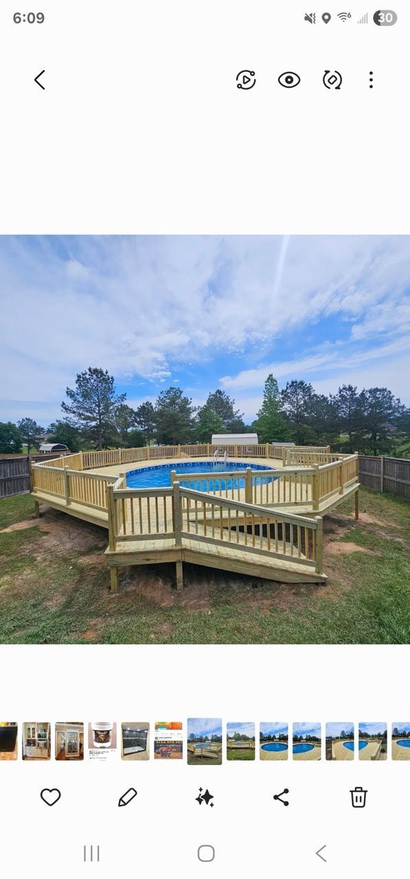 Wooden octagonal deck with a blue tarp-covered hot tub in a grassy yard under a cloudy sky